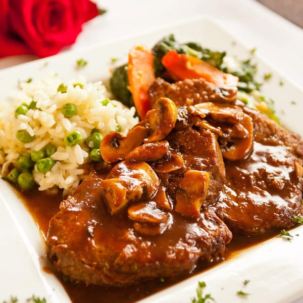 Veal Marsala with mushrooms, rice and peas, and vegetables, with a red rose in the background.